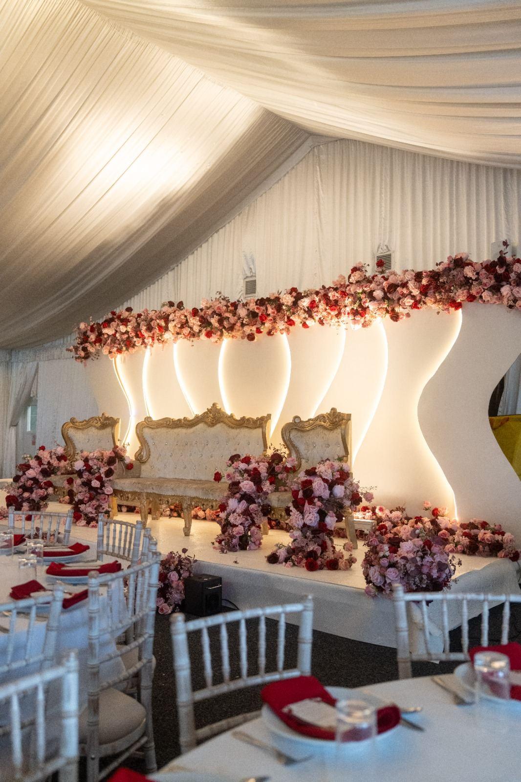 Wedding sweetheart stage with cascading red and pink florals